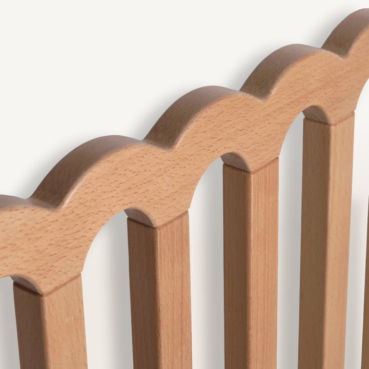 Close-up of a wooden baby gate with a scalloped edge on a white background