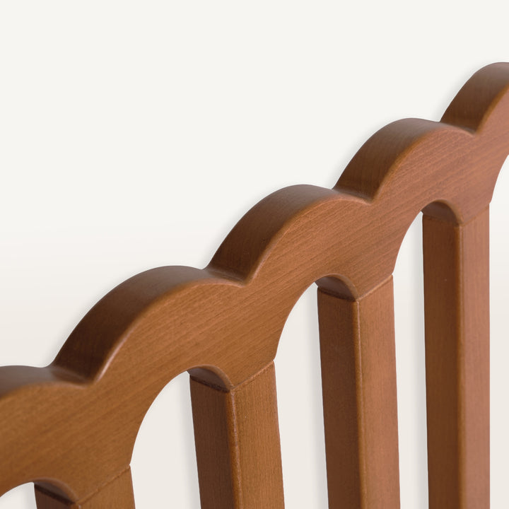 Close-up of a walnut baby gate with a scalloped edge on a white background
