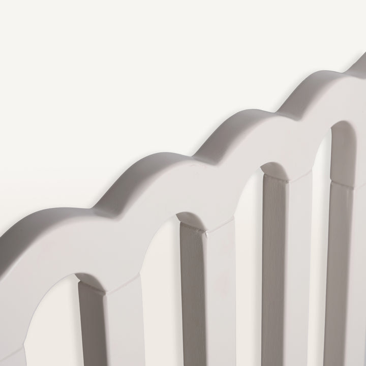Close-up of a baby gate with a scalloped edge on a white background