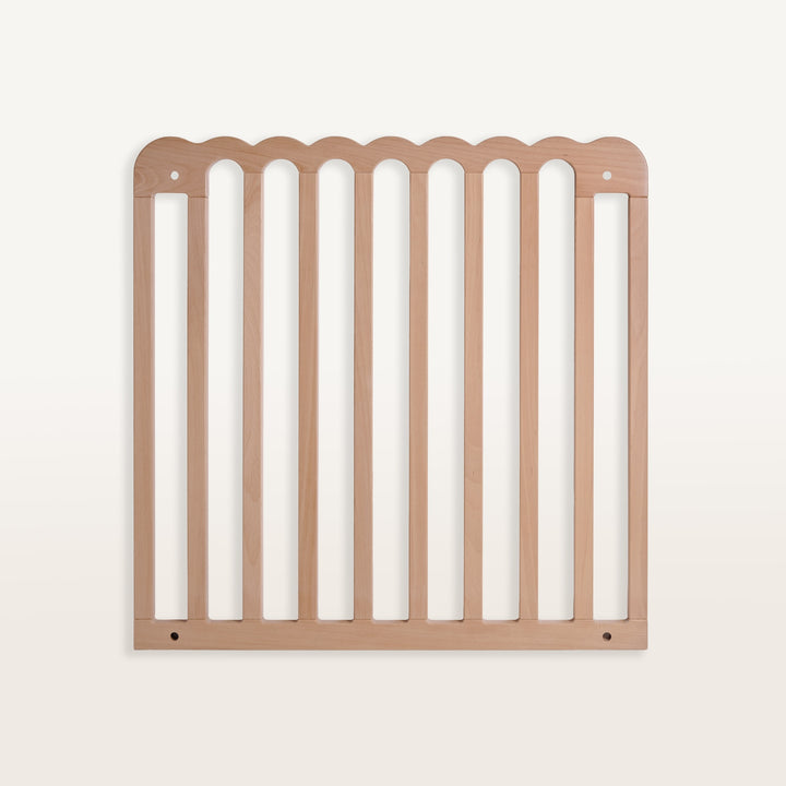Wooden pet gate with scalloped top edge on a white background