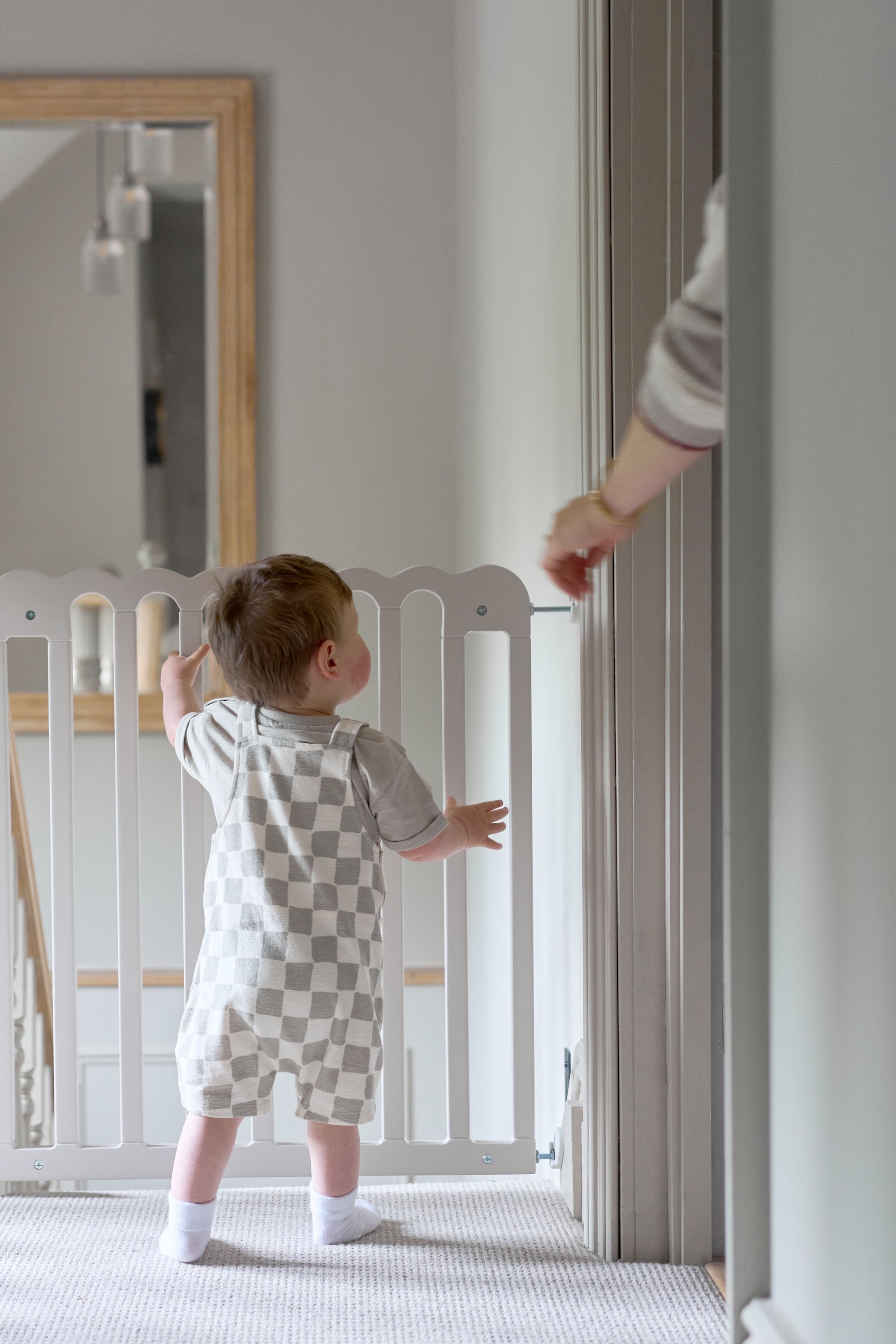 Baby standing next to a baby gate. Aesthetically pleasing baby gate.