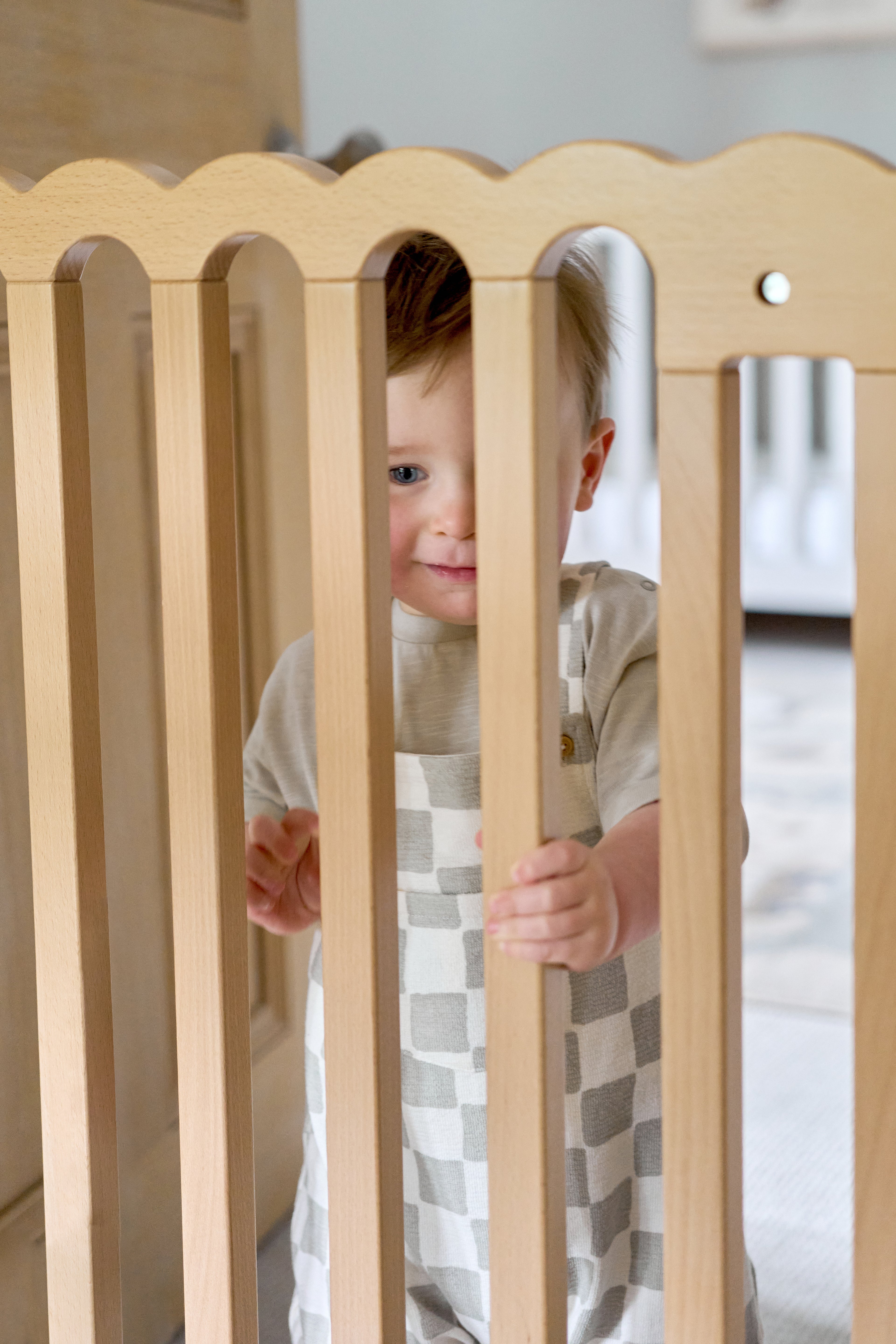 Child peeking through a pretty wooden baby gate.